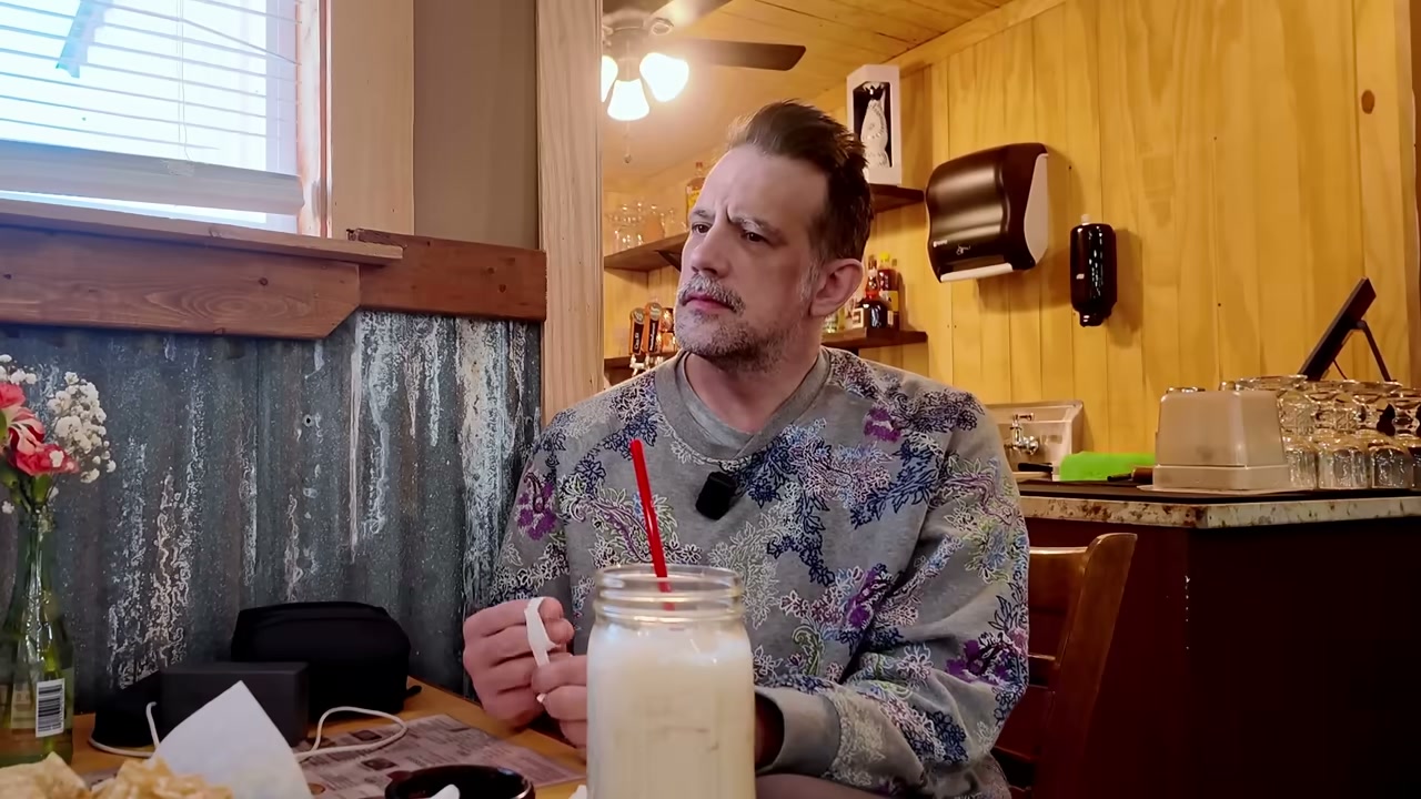 Man seated at restaurant table with milkshake