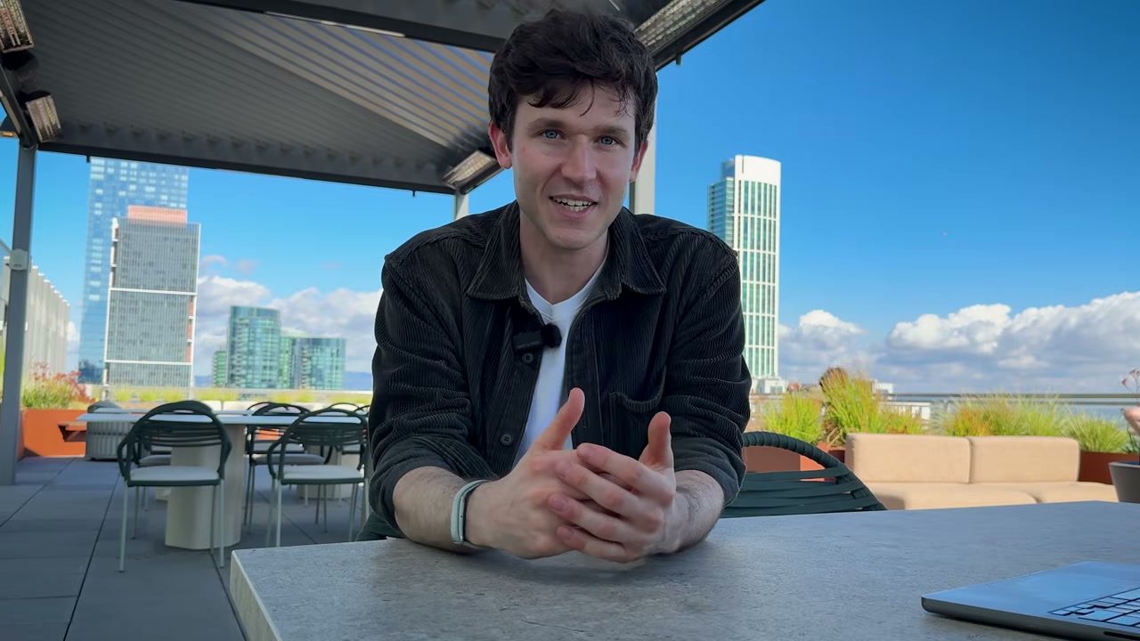 Man speaking at rooftop terrace table with city skyline